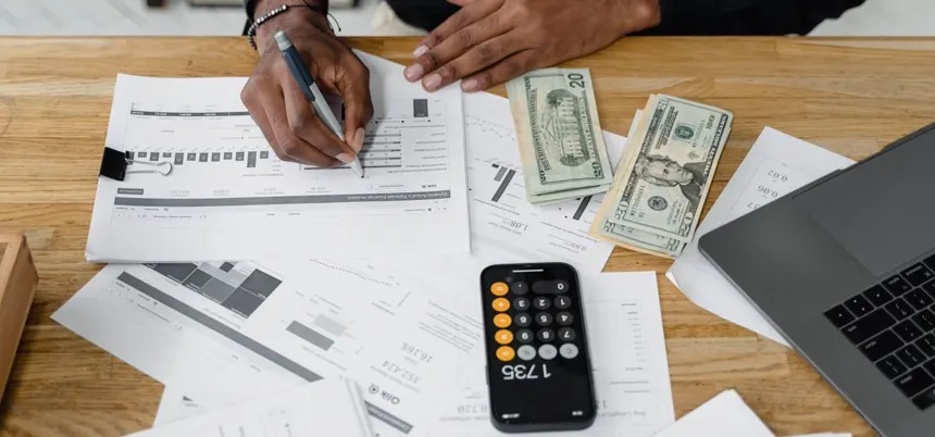 Contadora revisando reportes financieros con calculadora y laptop