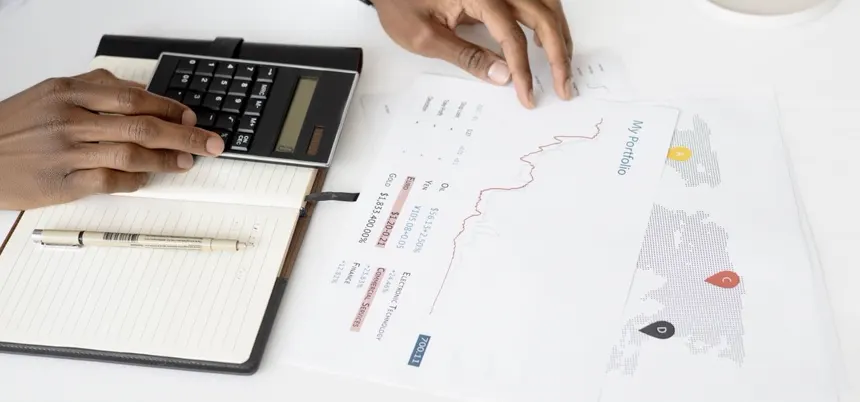 Manos con calculadora sobre reportes y gráficas